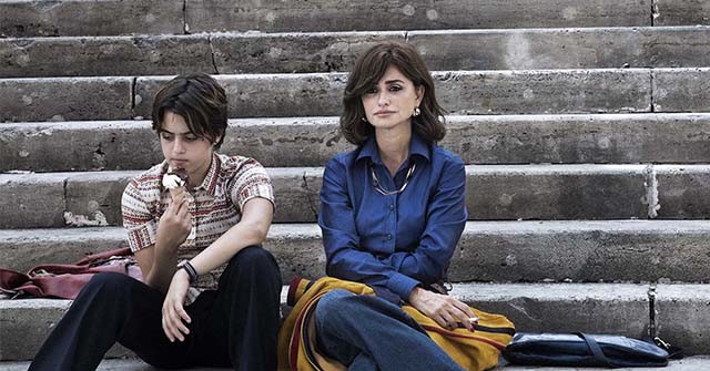 A still from the film L'Immensita, which shows actress Penelope Cruz sitting on steps next to a child.